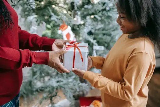 A joyful moment shared as a child receives a Christmas gift by the tree, capturing the holiday spirit.